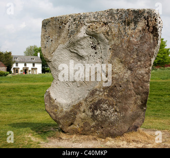 Massive Sarsen Monolith in der äußeren Steinkreis von Avebury in Wiltshire mit einem Haus im Dorf jenseits Stockfoto