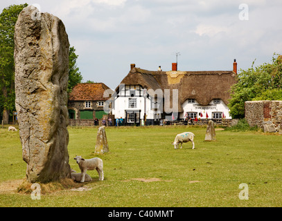 Massive Sarsen Monolith in eines der inneren Steinkreise von Avebury in Wiltshire mit der Red Lion Dorfkneipe Stockfoto