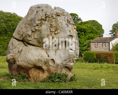 Massive Sarsen Monolith in eines der inneren Steinkreise von Avebury in Wiltshire mit einem Haus im Dorf jenseits Stockfoto