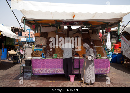 Trockenfrüchte-Verkäufer bei am Platz Djemaa al Fna mit zwei Kunden Stockfoto