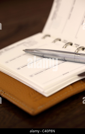 Nahaufnahme eines offenen Leather Filofax Tagebuchs mit einem silbernen Stift vor einem verschwommenen Hintergrund Stockfoto