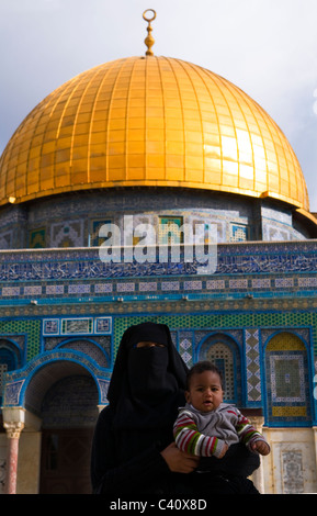 Eine verschleierte arabische Frau hält ihr Baby vor den Felsendom auf dem Tempelberg in Jerusalem. Stockfoto