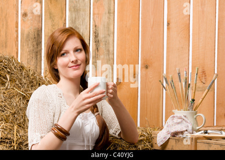 Junge rote Haare romantische Frau halten Tasse in Scheune Stockfoto