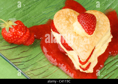 Herzförmige, Erdbeeren und Creme Millefeuille auf ein Erdbeer-sauce Stockfoto