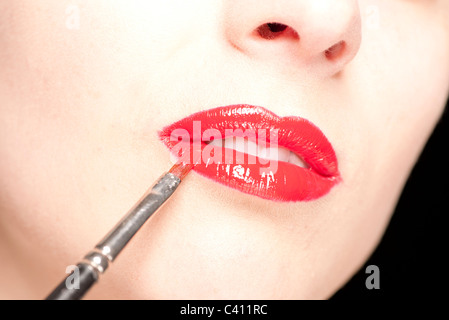 Frau roten Lipgloss mit einem Pinsel auftragen Stockfoto