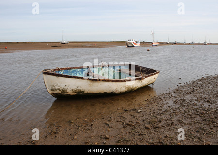 Ein gestrandetes Ruderboot, ein Fischerboot in den Schlammgebieten von Brancaster Staithe Norfolk Stockfoto