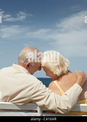 älteres kaukasischen paar auf Bank am Meer sitzen und umarmt. Vertikale Form, Rückansicht, Textfreiraum Stockfoto