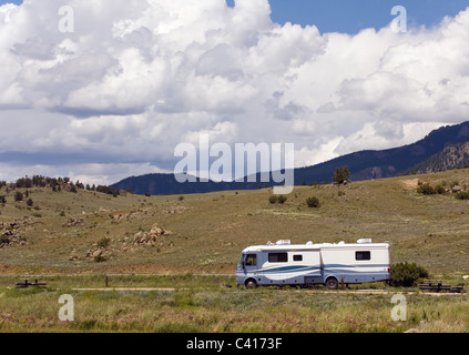 Ein Freizeitfahrzeug mit einem Slide-Out auf einem Campingplatz in den Bergen mit einem bewölkten Himmel Stockfoto