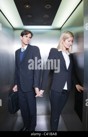 Profis, die Hand in Hand im Aufzug Stockfoto