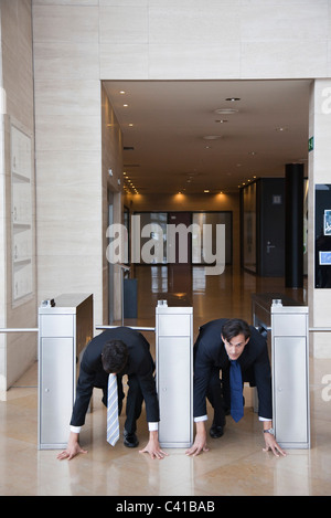 Geschäftsleute, die hocken in Ausgangsposition in Lobby Drehkreuze Stockfoto