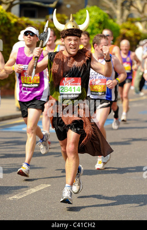 Läufer teilnehmen an die Jungfrau 2011 London-Marathon, gesehen hier bei 14 Meilen an einem sehr heißen Tag mit einem Läufer, gekleidet wie ein Wikinger Stockfoto