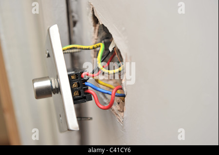 eine fehlerhafte Haus Licht dimmer-Schalter von Wand zeigt elektrische weggezogen Drähte parallel während DIY Stockfoto