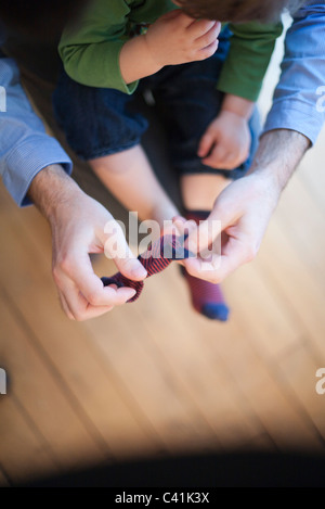 Vater helfen Kleinkind setzen auf Socken, beschnitten Stockfoto