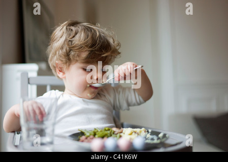 Kleinkind Jungen Fütterung selbst mit Löffel Stockfoto