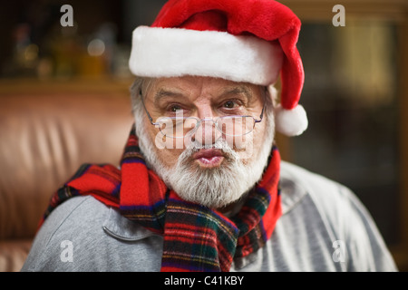 Ältere Mann trägt Weihnachtsmütze und weht einen Kuss Stockfoto