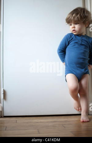 Kleinkind Jungen stehen auf einem Bein gegen Tür, Blick dachte darüber Weg, Porträt Stockfoto