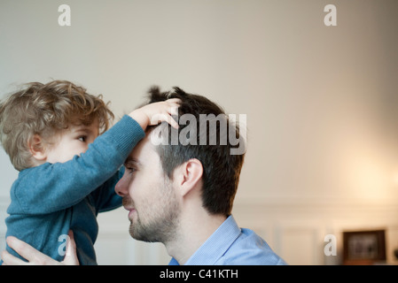 Kleinkind Jungen spielen mit Vaters Haar Stockfoto