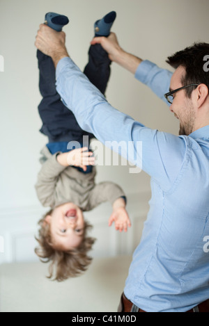 Vater Holding jungen Sohn kopfüber durch seine Knöchel Stockfoto