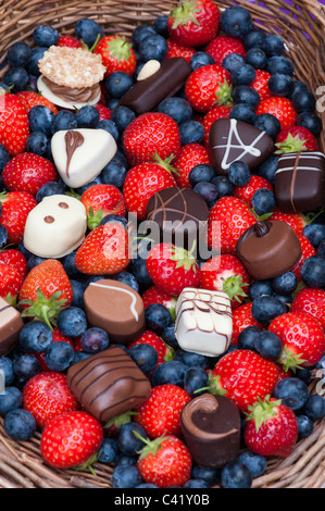 Erdbeeren, Blaubeeren und Schokolade in einem Weidenkorb Stockfoto