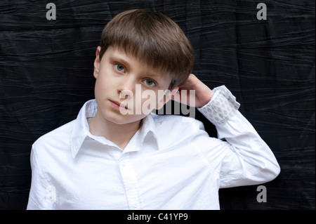 Porträt eines kleinen Jungen mit blonde Haare und blaue Augen mit der Hand angehoben und bekleidet mit einem weißen Hemd Stockfoto