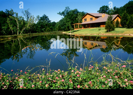 Schöne Zeder Holzes Haus spiegelt sich im Wasser des ruhigen Sommer See mit blühenden Klee an sonnigen Tag Stockfoto