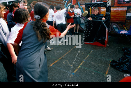 Kinder werfen nasse Schwämme für Comic Relief auf Schulhof Stockfoto