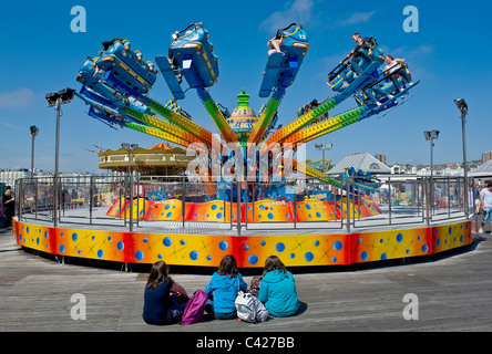 Drei junge Mädchen sitzt vor einem Messegelände fahren am Pier von Brighton Stockfoto