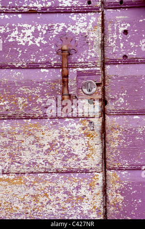 Hintergrund eines alten gemalt, zerbröckelte Tür. Griff auf lila Holzbohlen. Stockfoto