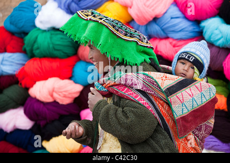 Peru, Huancarani, Frau und Kind vor Wolle zum Verkauf auf Markt. Stockfoto