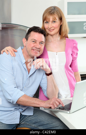 Glückliches Paar in der Küche mit Laptop, Kamera suchen. Stockfoto
