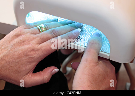 Lady erhalten eine Maniküre im Beauty-Salon-Einstellung Nagellack mit UV-Licht. Stockfoto