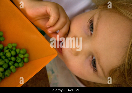 Junge Mädchen, die gerne essen Erbsen Stockfoto