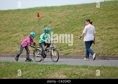 kleiner Junge auf seinem Fahrrad ziehen seine Schwester auf Inline - Skates hinter ihm Stockfoto