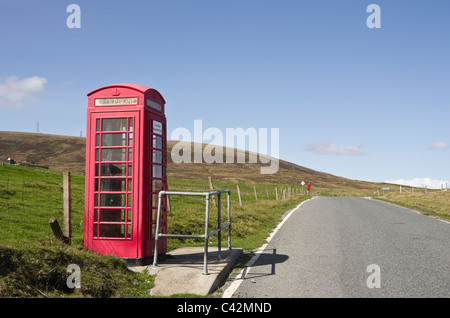 Eingleisig leeren Land Straße und rot Kiosk Telefonzelle. Voe, Northmavine, Shetland Islands, Schottland, UK, Großbritannien. Stockfoto