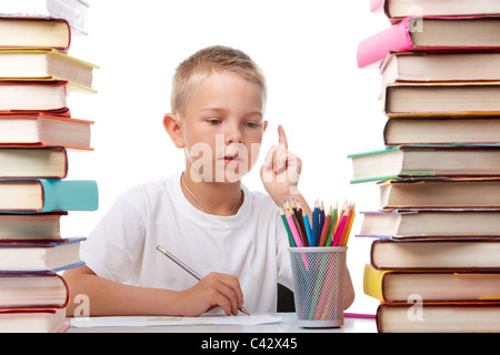 Porträt von niedlichen Youngster unter den Bücherstapel sitzen und denken während des Zeichnens Stockfoto