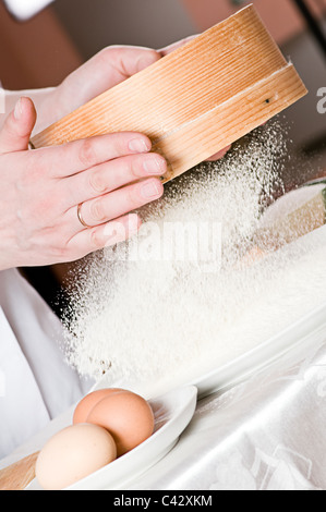 Sichtung durch ein Sieb für ein Backblech Mehl Stockfoto