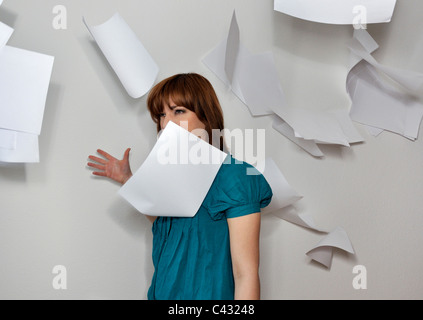 Junge Frau, die Papiere in die Luft werfen Stockfoto