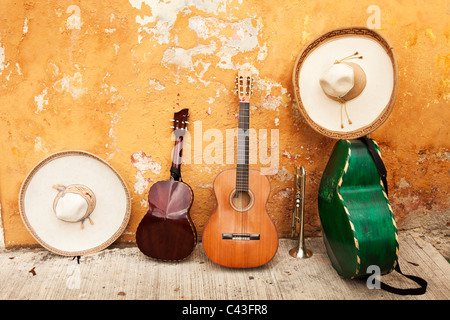 Mexikanische Musikinstrumente und Sombreros liegen an einer schäbigen Wand mit abblätternder Farbe Stockfoto