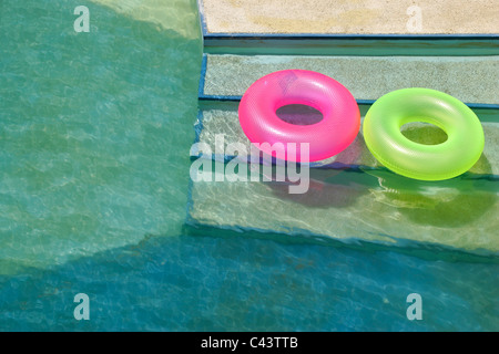 Zwei bunte rosa und grün ring Lilo Schwimmer im Freibad Stockfoto