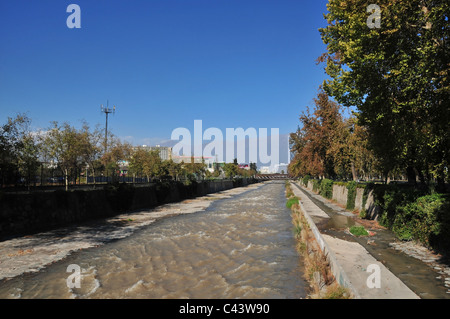 Blauer Himmel braun grün Herbst Bäume neben konkreten kanalisierten Rio Mapocho, flussaufwärts in Richtung Anden, Centro, Santiago, Chile Stockfoto