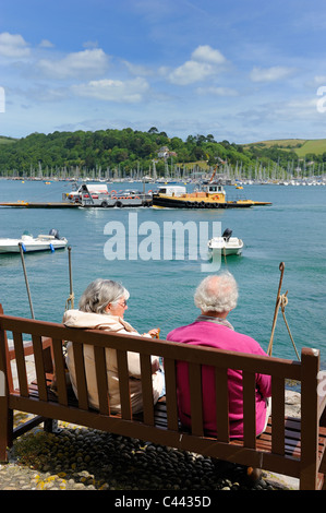 Ein altes Ehepaar sitzt auf einer Bank, Blick auf Kingswear Devon England uk Stockfoto