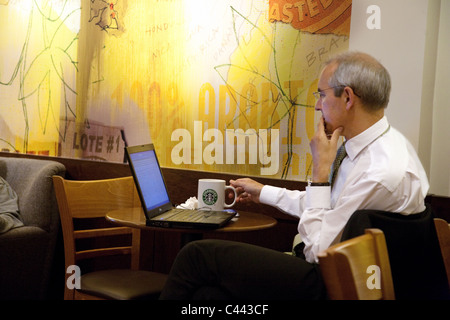 Ein Geschäftsmann auf seinem Laptop in Starbucks Coffee Bar arbeiten, Dienstleistungen mimbar Autobahn M4, Wiltshire, UK Stockfoto