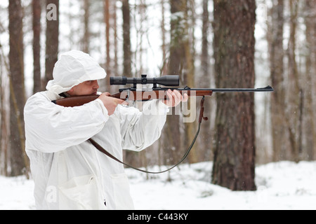 Scharfschützen in weiße Tarnung mit Gewehr im Winterwald. Stockfoto