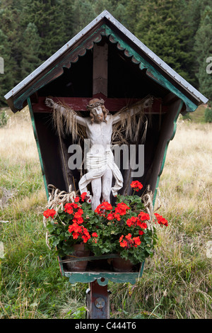 Ein Kruzifix und Blumen in einer Holzkonstruktion Stockfoto