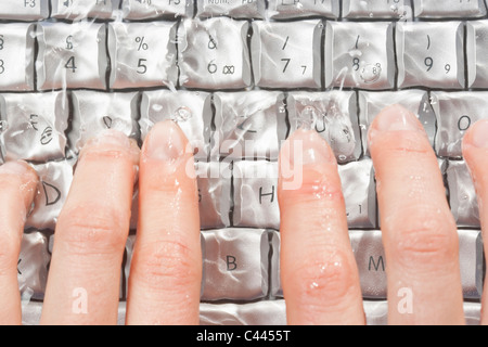 Detail der Hände Tippen auf einen Laptop unter Wasser Stockfoto