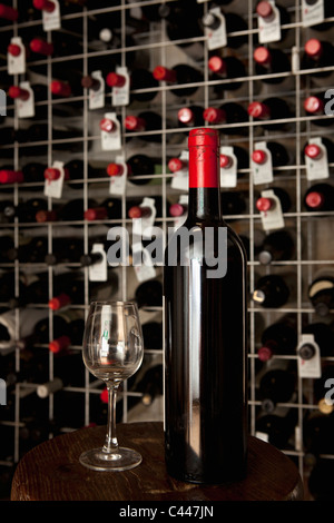 Eine Flasche Wein und ein Weinglas in einem Keller Stockfoto