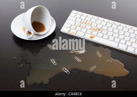 Eine Tasse Kaffee verschüttet auf einer Computertastatur Stockfoto