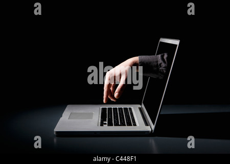 Eine Hand greift über ein Notebook, das über die Tastatur eingeben Stockfoto