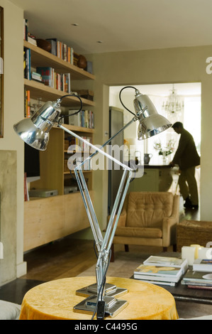 Zwei Anglepoise-Leuchten auf einem runden Tisch im Wohnzimmer mit Buch-Regal Stockfoto