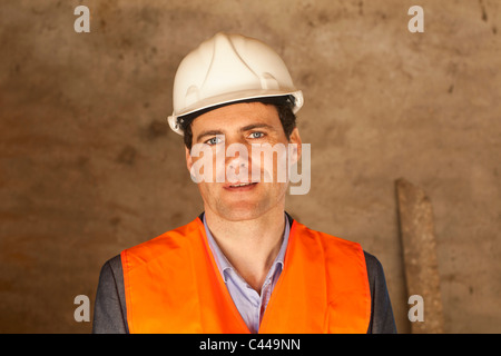 Ein gut gekleideter Mann mit einem Bauarbeiterhelm und reflektierende Weste auf einer Baustelle Stockfoto
